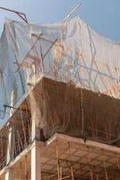 New building construction process. Safety nets and structural beams highlight ongoing work. Detailed shot of multi-level architecture. Ideal for articles on urban development, real estate investment. photo