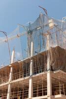 New building construction process. Safety nets and structural beams highlight ongoing work. Detailed shot of multi-level architecture. Ideal for articles on urban development, real estate investment. photo