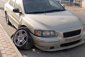 Severe damage to grey car's side after a collision, showcasing a crumpled door and detached bumper. Ideal for use in insurance claims, automotive repair tutorials, and road safety awareness materials. photo