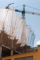 New building construction process. Safety nets and structural beams highlight ongoing work. Detailed shot of multi-level architecture. Ideal for articles on urban development, real estate investment. photo