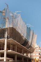 New building construction process. Safety nets and structural beams highlight ongoing work. Detailed shot of multi-level architecture. Ideal for articles on urban development, real estate investment. photo