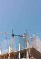 New building construction process. Safety nets, structural beams highlight ongoing work. Multi-level architecture. Ideal for articles on urban development, real estate investment. Copy space for text. photo
