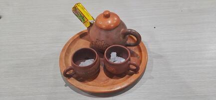 Teh Gopek or Teh Poci, traditional drink from Tegal City Central Java Indonesia. Set of Pottery Tea or Clay Pot with Rock Sugar. Bekasi, West Java, Indonesia - June 10 2024 photo