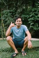 A Southeast Asian man makes a hand gesture as if talking on a phone, conveying a playful and communicative moment photo