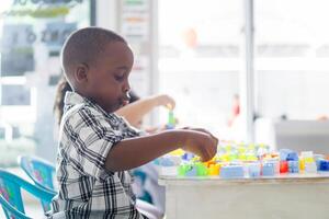 Portrait side view of little african boy enjoying with colored blocks. photo