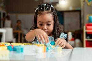 portrait of latin american little child playing with colored block photo