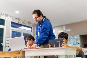 Teacher in class teaching student how use a laptop. photo