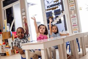 Three little children with your hands up in a class. photo