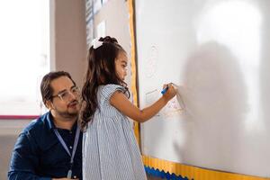 Little girl learn front a whiteboard. geographical forms concept. photo