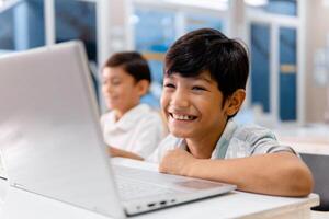 Portrait school cheerful boy using digital device in school classroom. photo