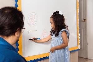 Little girl learn front a whiteboard. geographical forms concept. photo