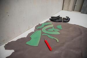 Work table to produce shoes with leather and lasts and a cutter, fashion industry photo