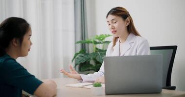 Handheld dolly shot, Asian doctor explains health problem of young female patient in clinic office, Health and medicine consultant, conversation about healthcare video