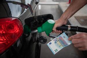 Hand of a man refueling the car and holding a 20euros banknote, concept of rising fuel prices. photo