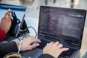 Female programmer writes some code and drinks coffee while sitting near her colleague. photo