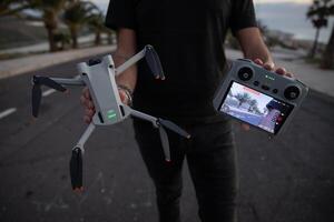 Tenerife, Spain, 27th January 2023. A drone pilot holding the new DJI mini 3 Pro drone and its remote controller with screen. photo