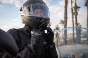An African biker wears a helmet while sitting on his motorcycle, road safety. photo
