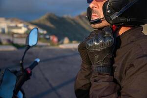 A motorcyclist puts on his helmet while sitting on his motorcycle. photo