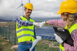 Two engineers punch each other at the solar power station, teamwork concept photo