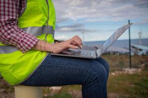 An engineer uses her laptop at a solar power plant, photo with copy space