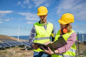 Two engineers at work analyze data in the solar farm, female and male coworkers photo