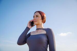 A young woman makes a phone call with the clear sky as background photo
