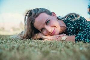 Portrait of a smiling woman with blue eyes lying on a meadow photo