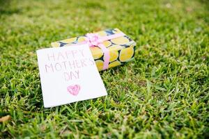 A card with written Happy Mother's Day placed on a gift, photo with copy space