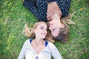 Mother and daughter laying on the grass smiling, photo from above with copy space