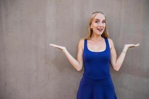 Attractive woman with surprised expression and raised arms, model isolated on grey background photo