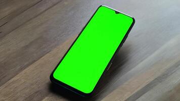 A mobile phone with a green screen simulates lying on a table. video