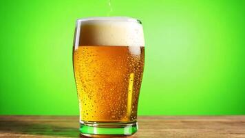 A glass of beer with frothy head being placed on a table. Green screen backdrop. Bright, even lighting to reflect a pub setting. video