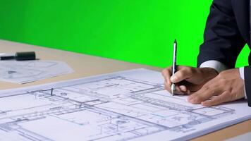 An architect at a desk, sketching blueprints. Green screen backdrop. Professional office lighting. video