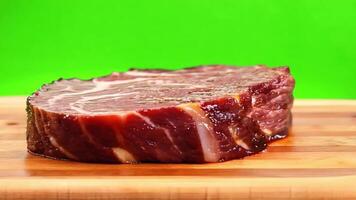 A hand slicing a juicy steak on a cutting board. Green screen backdrop. Bright, even lighting to reflect a kitchen setting. video