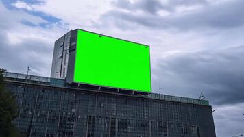 A large billboard with a green screen on the building wall. video