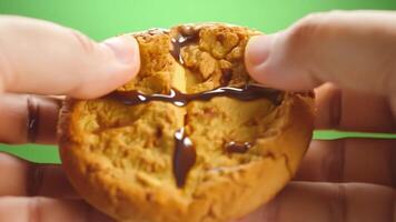 A freshly baked chocolate chip cookie being broken in half, revealing a gooey center. Green screen backdrop. Soft, diffused lighting to create a homey feel. video