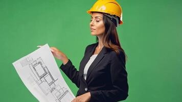 A Female engineer wearing a yellow hard hat Hold the blueprint and point at the project. green backdrop video