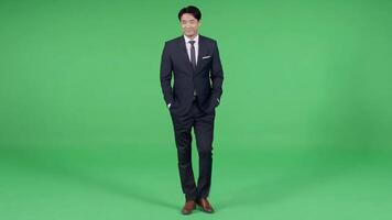 Handsome business asia man walking with his hands in pockets on a uniform Green Screen, Chroma Key. video
