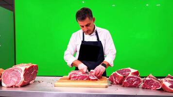 A butcher in an apron, cutting meat. Green screen backdrop. Bright, even lighting to reflect a store environment. video