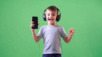Happy toothless boy dancing with headphones on and smartphone in hand isolated on green screen background. video
