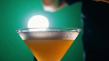A bartender garnishing a cocktail with a citrus twist. Green screen backdrop. Spotlight lighting to highlight the action. video
