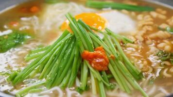 A bowl of ramen with steaming broth, noodles, and assorted toppings being garnished. Green screen backdrop. Bright, even lighting to highlight the vibrant colors. video