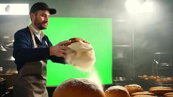 A baker dusting a freshly baked loaf of bread with flour. Green screen backdrop. Soft, diffused lighting to create a rustic feel. video