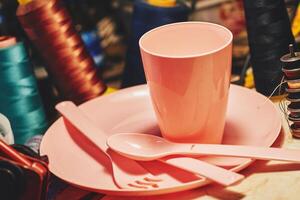 Pink plastic dinnerware set in tailor sewing workshop.Cup,fork,knife,spoon photo