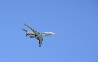 Private jet against the blue sky as it approaches Nice, France photo