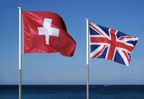 The national flags of Switzerland and the United Kingdom next to the sea photo
