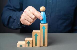 A man places a figurine of a man at the top of the stairs. Promote a worker for excellent performance. Reach the highest level of your career. Achieve success. photo
