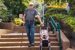 Elderly man walking down the stairs with a walking stick. photo