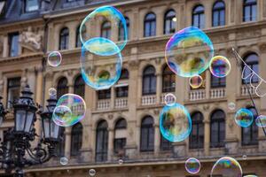 Many multicolored giant soap bubbles flying in the air on a windy day. Huge bubble are stretching on the wind into long smoothy changing form without popping. Close up. Copy space. Selective focus. photo