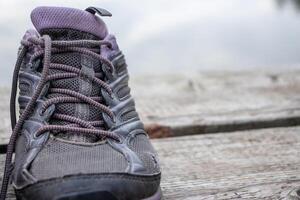 Close up of one forgotten single worn out sport shoe on a old wooden deck floor on the lake beach. Autumn cloudy day in nature. Active lifestyle, running, marathon concept. Copy space, selective focus photo